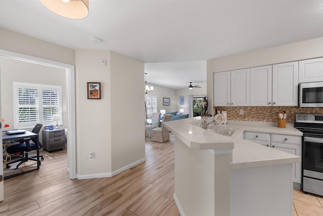 kitchen featuring a sink, light wood finished floors, stainless steel appliances, open floor plan, and a peninsula