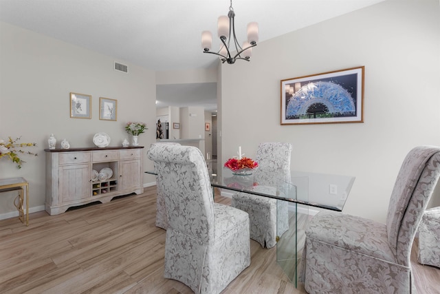 dining space with baseboards, a notable chandelier, visible vents, and light wood-style flooring