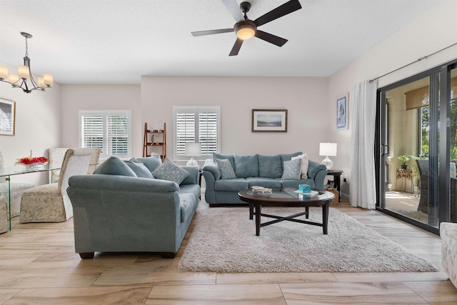 living area featuring ceiling fan with notable chandelier and light wood-type flooring
