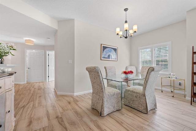 dining space featuring baseboards, a notable chandelier, and light wood-style floors