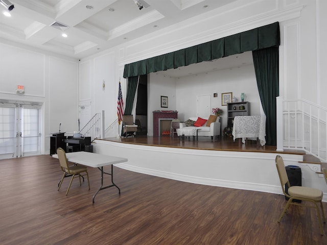 interior space with a decorative wall, a high ceiling, coffered ceiling, wood finished floors, and beamed ceiling