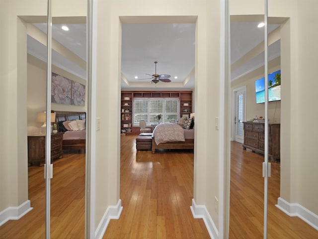 bedroom featuring recessed lighting, a raised ceiling, baseboards, and wood finished floors