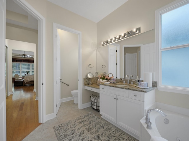 full bathroom with tile patterned flooring, toilet, a garden tub, vanity, and baseboards