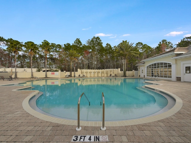 community pool with a patio area and fence