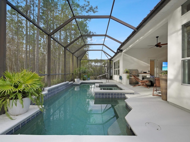 view of swimming pool featuring a pool with connected hot tub, an outdoor kitchen, a patio area, a grill, and a lanai