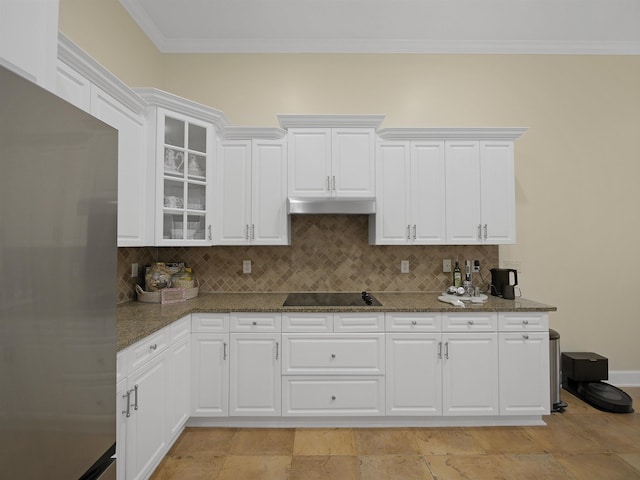 kitchen featuring white cabinets, glass insert cabinets, freestanding refrigerator, black electric stovetop, and under cabinet range hood