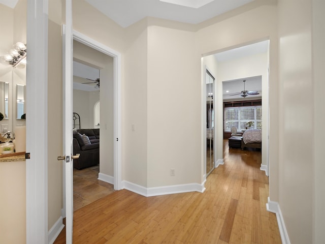 hallway featuring light wood-style flooring and baseboards