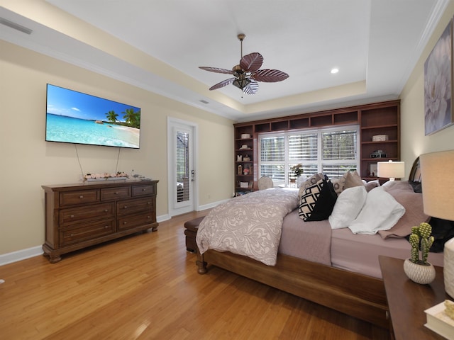 bedroom with access to exterior, light wood-style flooring, a tray ceiling, and baseboards