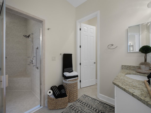 full bath featuring a stall shower, tile patterned flooring, vanity, and baseboards