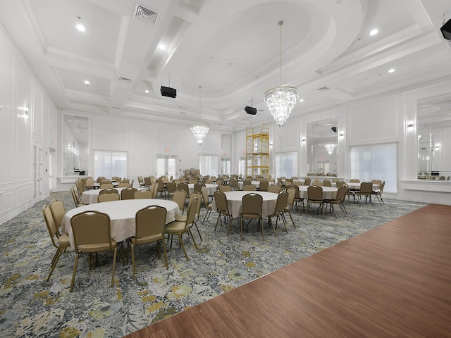 dining area featuring visible vents, wood finished floors, crown molding, a chandelier, and a decorative wall