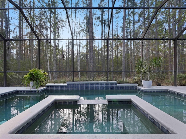 view of pool with a lanai and a pool with connected hot tub