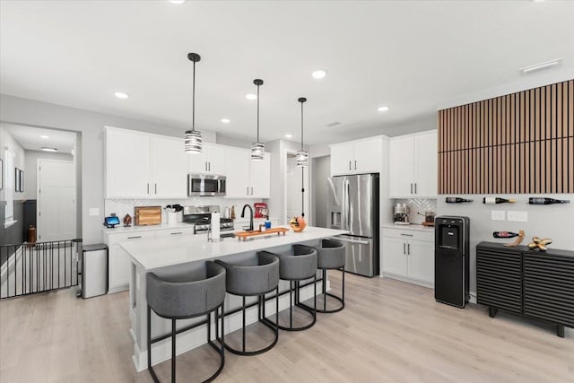 839 Lightsey Crossing Ln, Saint Augustine, FL 32084 - kitchen with backsplash, light countertops, a breakfast bar area, stainless steel appliances, and light wood-style floors