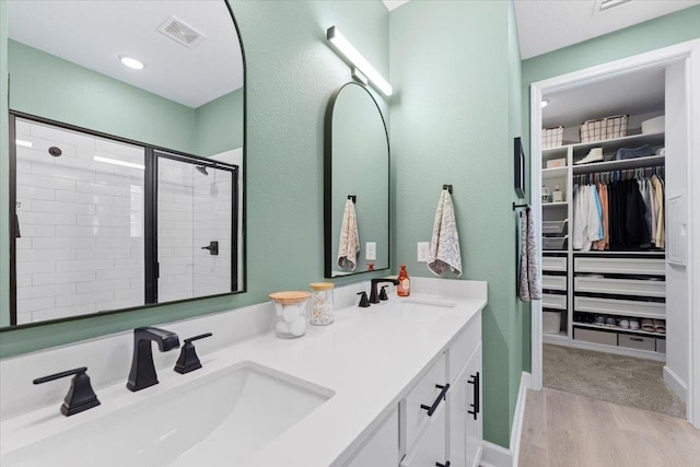 839 Lightsey Crossing Ln, Saint Augustine, FL 32084 - bathroom with double vanity, a spacious closet, a stall shower, and wood finished floors