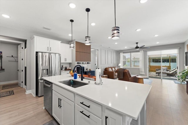839 Lightsey Crossing Ln, Saint Augustine, FL 32084 - kitchen with open floor plan, a ceiling fan, stainless steel appliances, light wood-style floors, and white cabinets