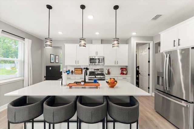 839 Lightsey Crossing Ln, Saint Augustine, FL 32084 - kitchen with appliances with stainless steel finishes, light wood finished floors, backsplash, light countertops, and a kitchen bar