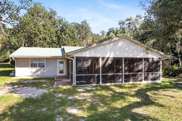 rear view of property featuring a sunroom and a yard