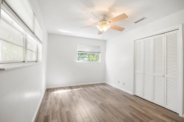 unfurnished bedroom featuring a closet, ceiling fan, light hardwood / wood-style flooring, and a textured ceiling