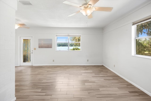 spare room featuring a wealth of natural light, light hardwood / wood-style flooring, a textured ceiling, and ornamental molding