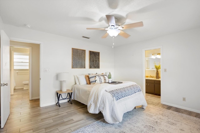 bedroom featuring light wood-type flooring, ceiling fan, and connected bathroom