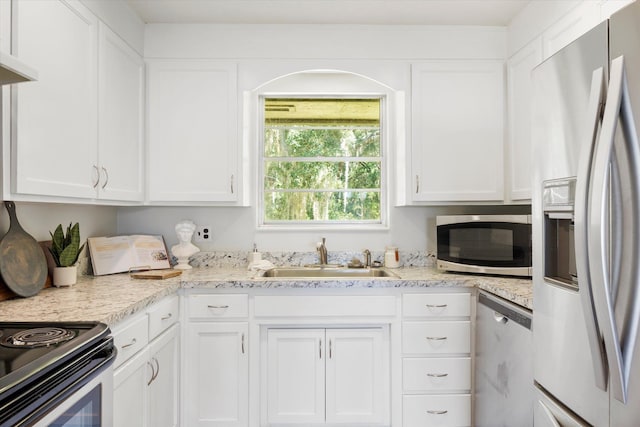 kitchen with appliances with stainless steel finishes, light stone counters, exhaust hood, sink, and white cabinets