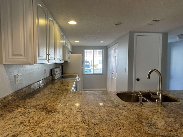 8130 A1A S Unit D-2, Saint Augustine, FL 32080 - kitchen with visible vents, white appliances, stone countertops, a textured ceiling, and a sink