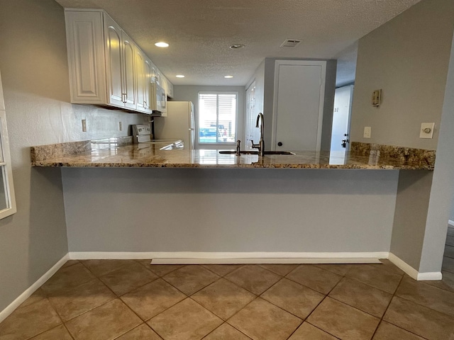 8130 A1A S Unit D-2, Saint Augustine, FL 32080 - kitchen with visible vents, a sink, white appliances, a peninsula, and light stone countertops