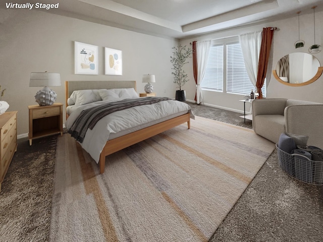 bedroom with carpet floors and a tray ceiling