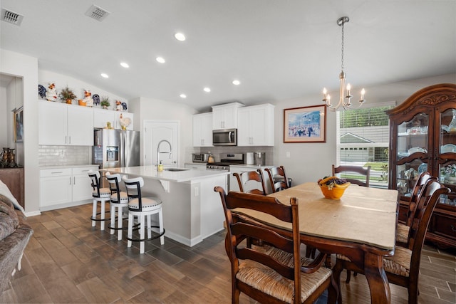 dining space with a chandelier, dark hardwood / wood-style flooring, vaulted ceiling, and sink