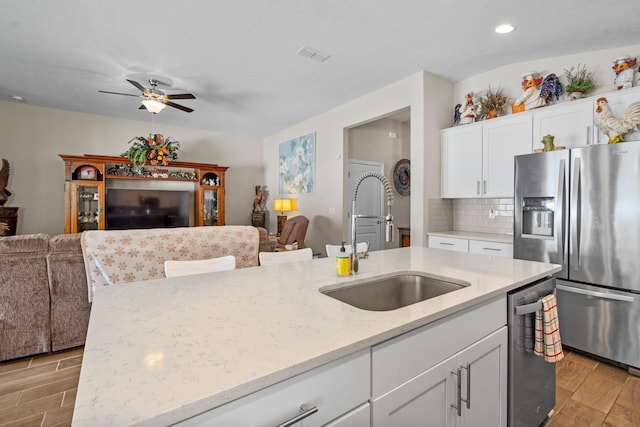 kitchen with appliances with stainless steel finishes, light wood-type flooring, a kitchen island with sink, and sink