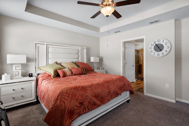 carpeted bedroom featuring ceiling fan and a raised ceiling