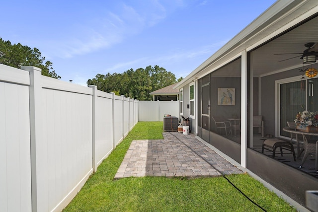 view of yard with central AC, a sunroom, ceiling fan, and a patio