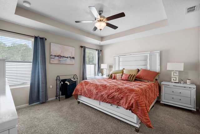 bedroom with a tray ceiling, ceiling fan, carpet flooring, and a textured ceiling