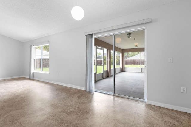 unfurnished room with baseboards and a textured ceiling