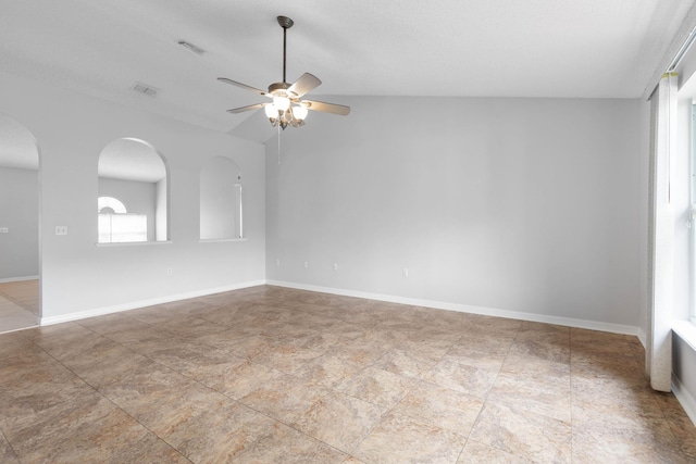 unfurnished room with visible vents, a ceiling fan, baseboards, and arched walkways