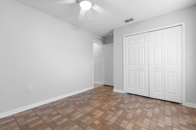 unfurnished bedroom featuring a closet, visible vents, a textured ceiling, and baseboards