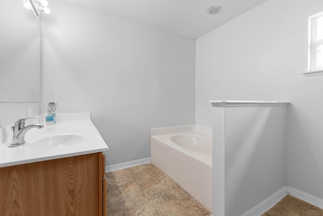 bathroom featuring vanity, a bath, and baseboards