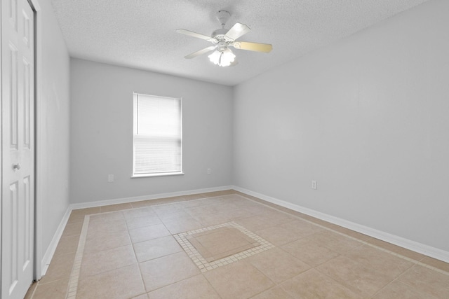 spare room with light tile patterned floors, baseboards, a textured ceiling, and a ceiling fan