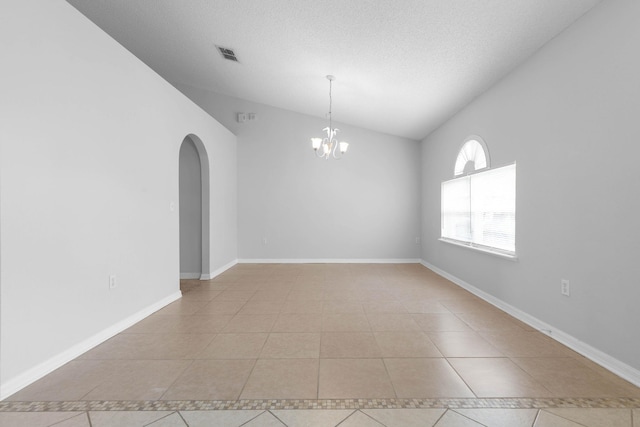 spare room featuring light tile patterned floors, baseboards, visible vents, arched walkways, and a chandelier