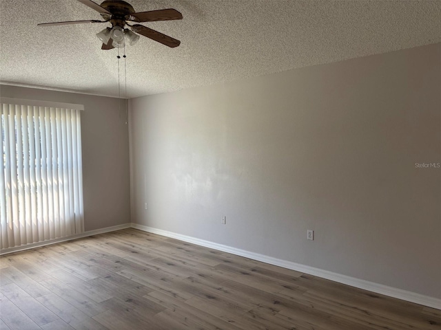 spare room with a textured ceiling, wood finished floors, baseboards, and ceiling fan