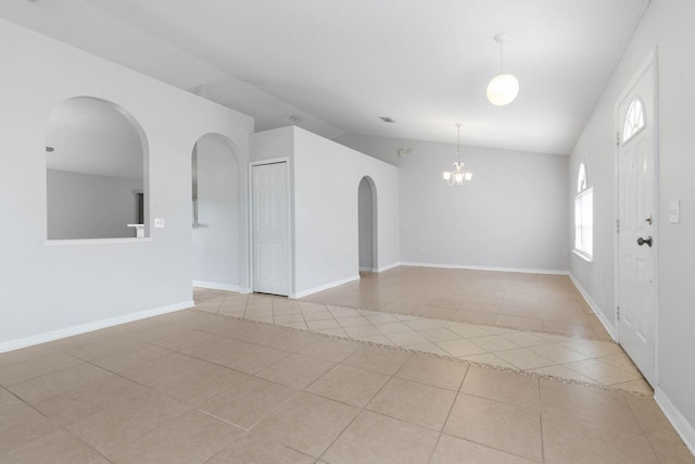 empty room featuring baseboards, lofted ceiling, arched walkways, an inviting chandelier, and tile patterned floors