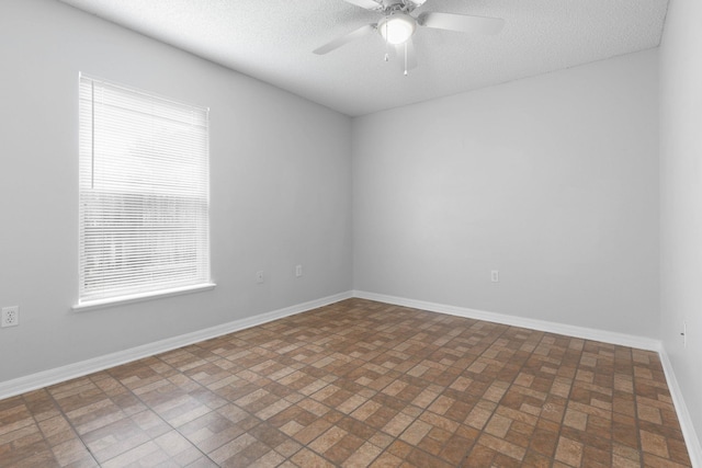 unfurnished room featuring baseboards, a textured ceiling, and a ceiling fan