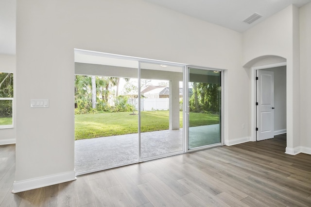 doorway to outside with a high ceiling, hardwood / wood-style flooring, and a wealth of natural light