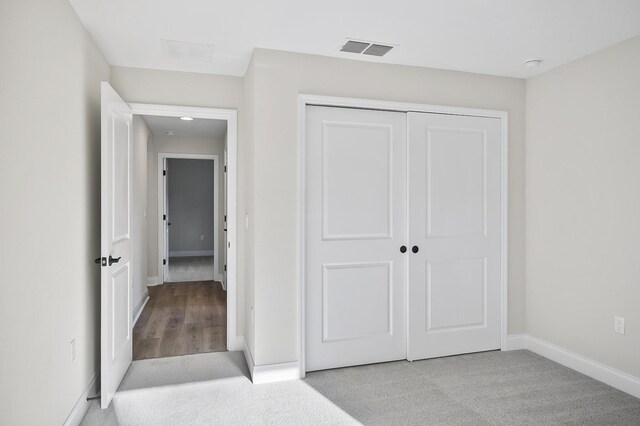 unfurnished bedroom with a closet and light colored carpet