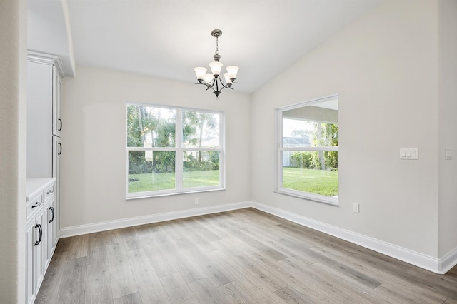 unfurnished dining area featuring a notable chandelier, light wood-type flooring, and lofted ceiling