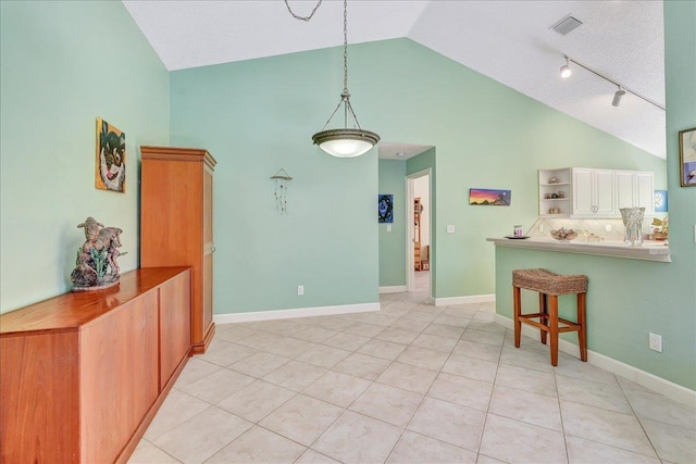 interior space with a breakfast bar, white cabinets, light tile patterned floors, decorative light fixtures, and kitchen peninsula