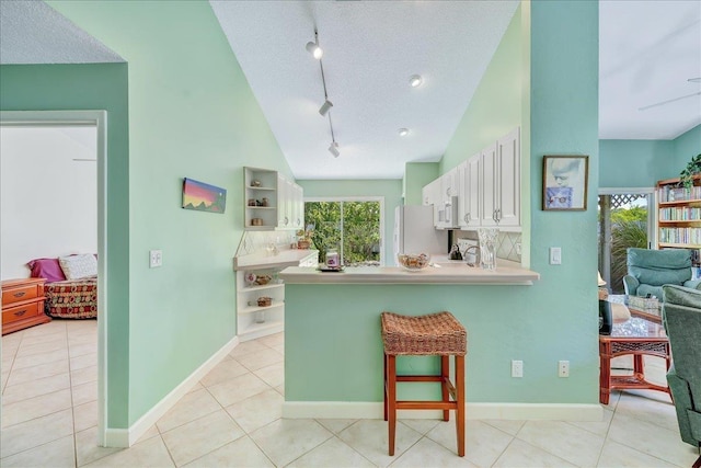 kitchen featuring kitchen peninsula, rail lighting, white appliances, a textured ceiling, and white cabinets