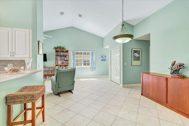 kitchen featuring backsplash, high vaulted ceiling, white cabinetry, hanging light fixtures, and light tile patterned flooring