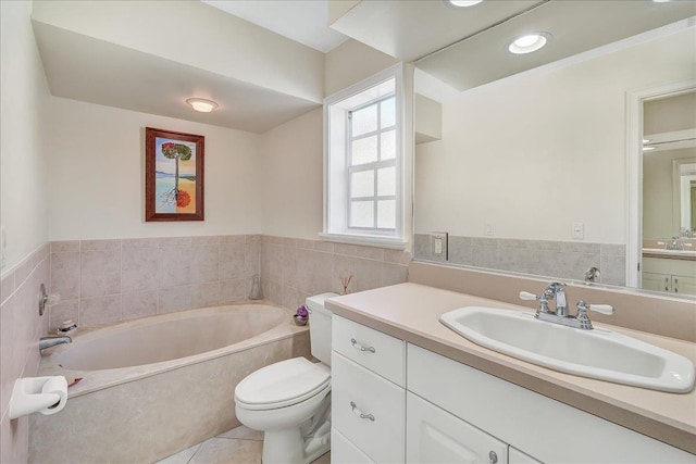 bathroom with a tub, tile patterned flooring, toilet, vanity, and tile walls