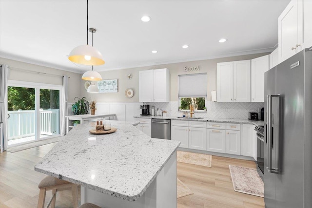 633 W Pope Rd, Saint Augustine, FL 32080 - kitchen with appliances with stainless steel finishes, white cabinets, a kitchen breakfast bar, backsplash, and crown molding
