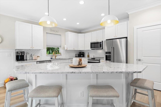 633 W Pope Rd, Saint Augustine, FL 32080 - kitchen featuring stainless steel appliances, crown molding, white cabinetry, tasteful backsplash, and a kitchen bar